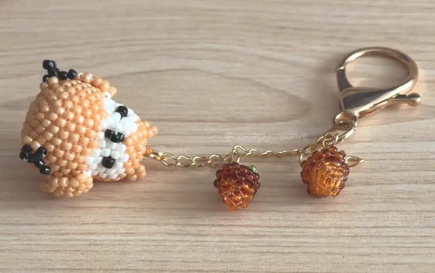 Two finished 3D beaded mini acorns hanging from a gold keychain chain with a 3D beaded animal charm and a gold lobster clasp